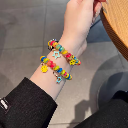Colorful beaded bracelet with charms on a wrist against a neutral background